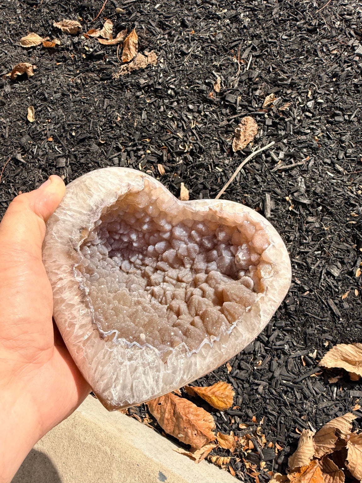 Heart geode held in hand showing sparkling druzy cavity